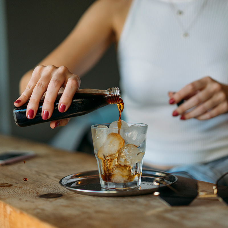 woman pouring cold brew coffee into an iced glass